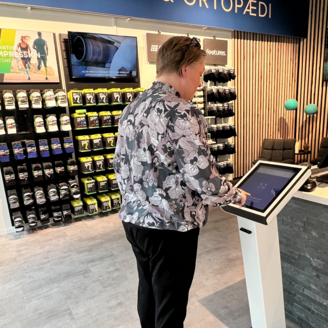 Elektronisk kønummersystem i butik med QR-kode og fysisk stander