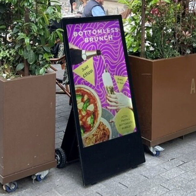 Fritstående batteridrevet display står på gaden ved en restaurant