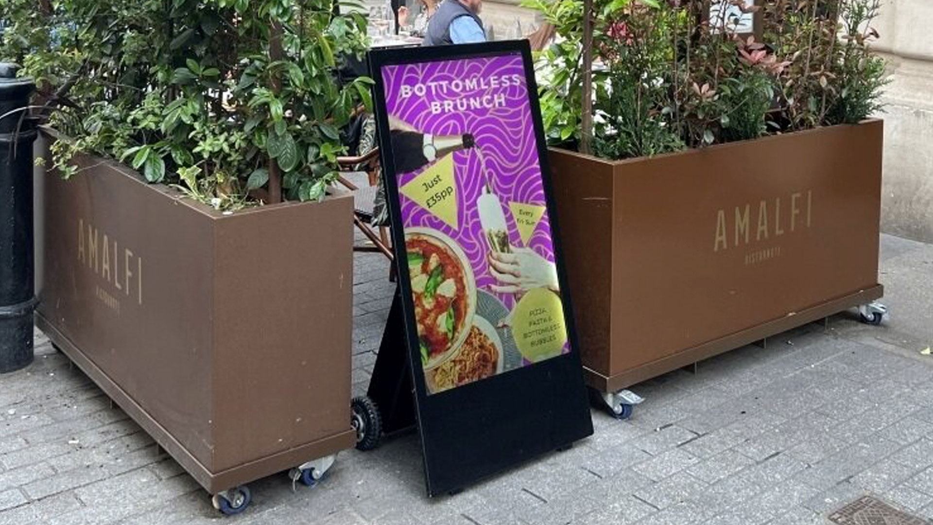 Fritstående batteridrevet display står på gaden ved en restaurant